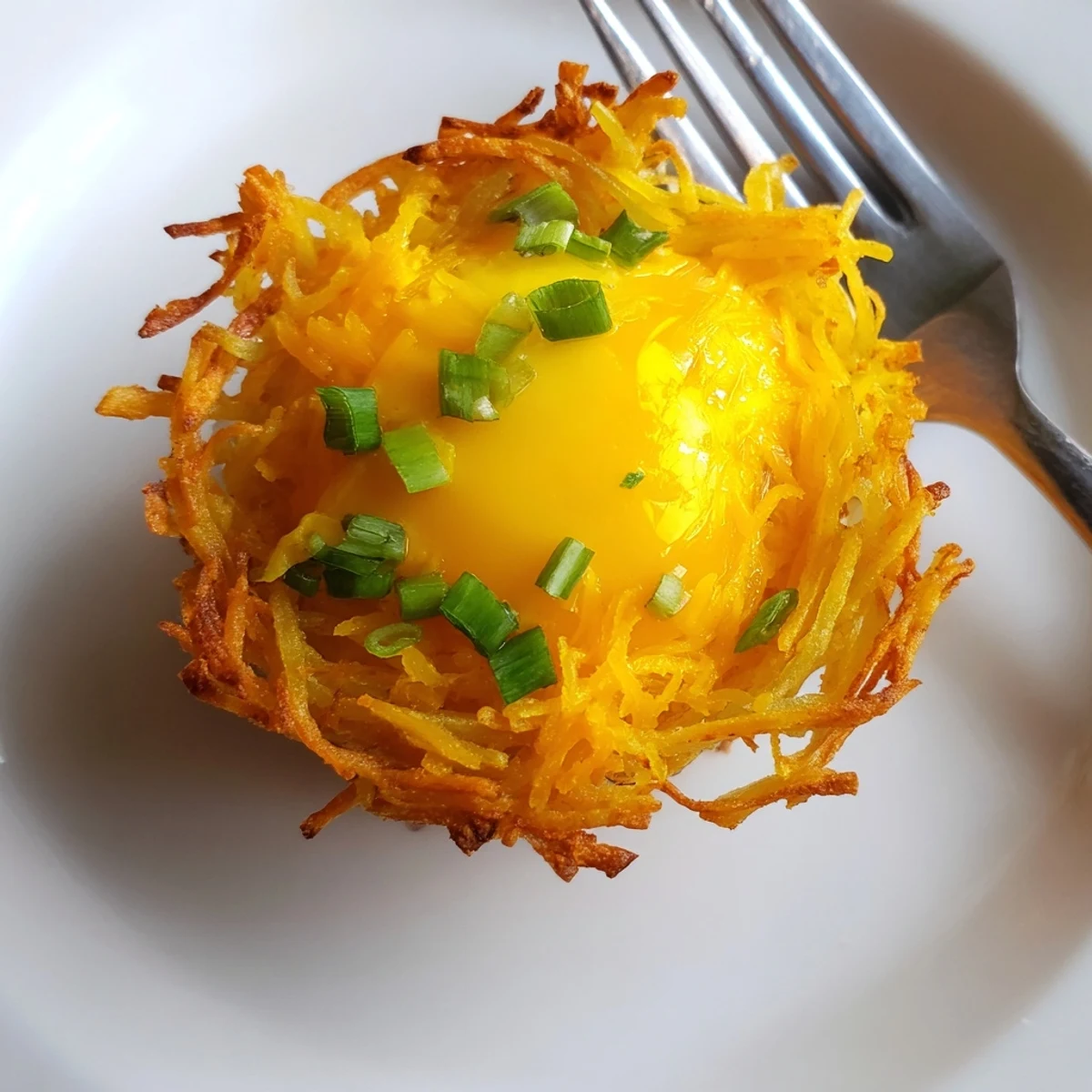 Golden, crispy Crispy Hashbrown Egg Nests overflowing with melted cheese and a perfectly cooked egg.