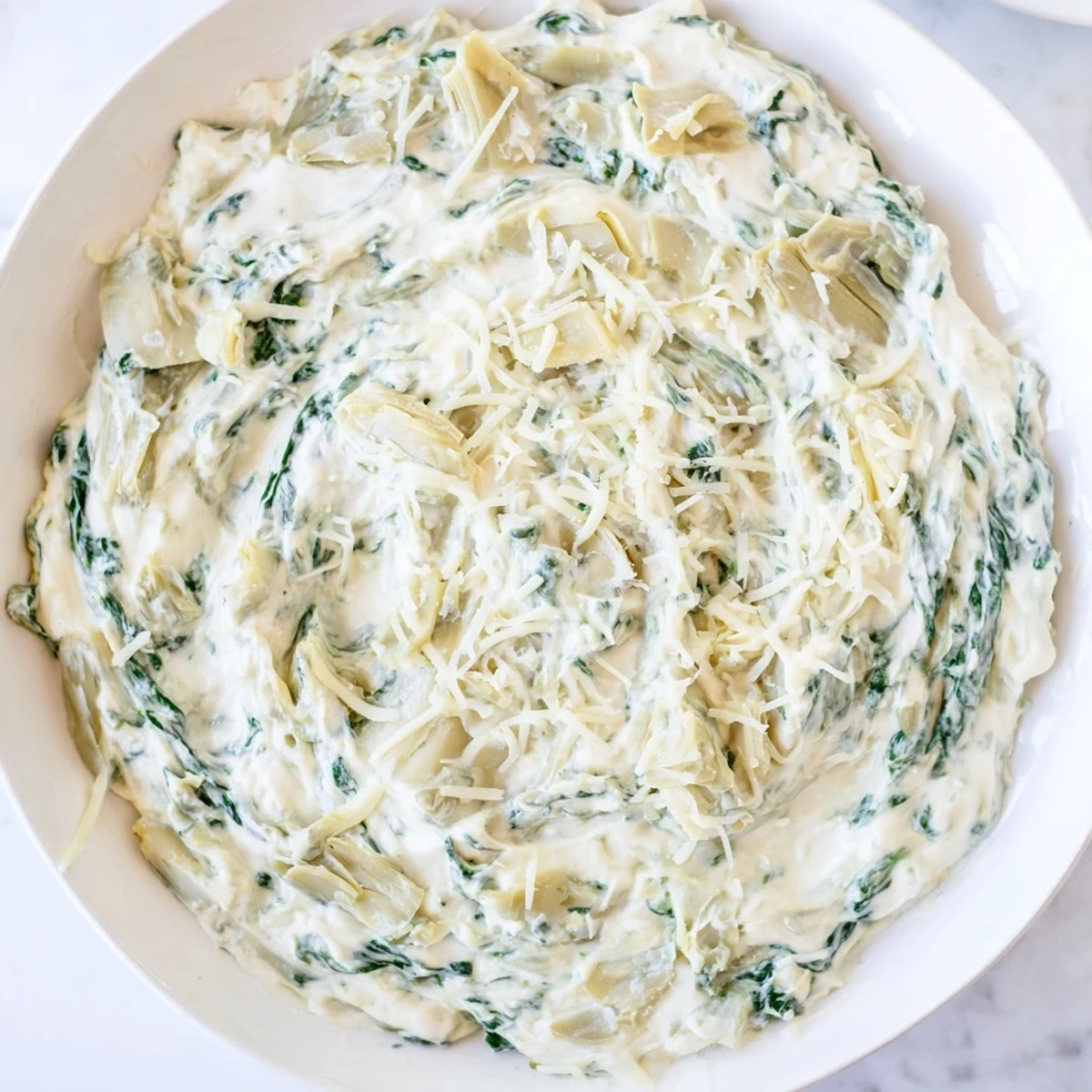 A close-up of Spinach Artichoke Dip, showing melting cheese and tender artichoke hearts, delicious.