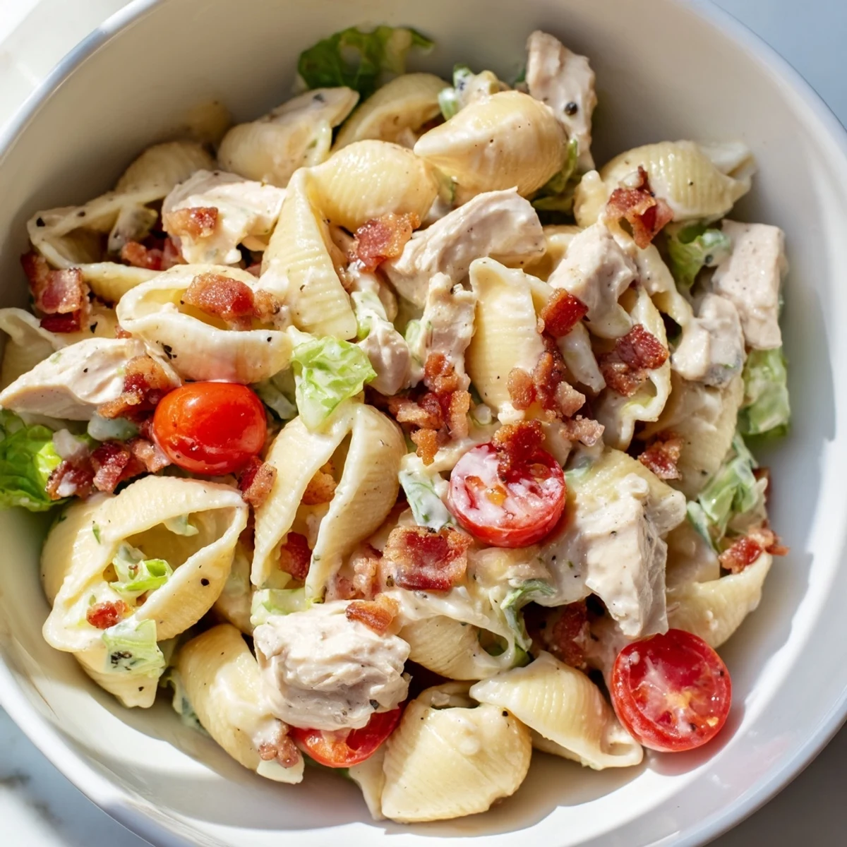 Close-up of BLT Chicken Pasta Salad showing tender pasta, diced grilled chicken, crunchy bacon, and vibrant greens.