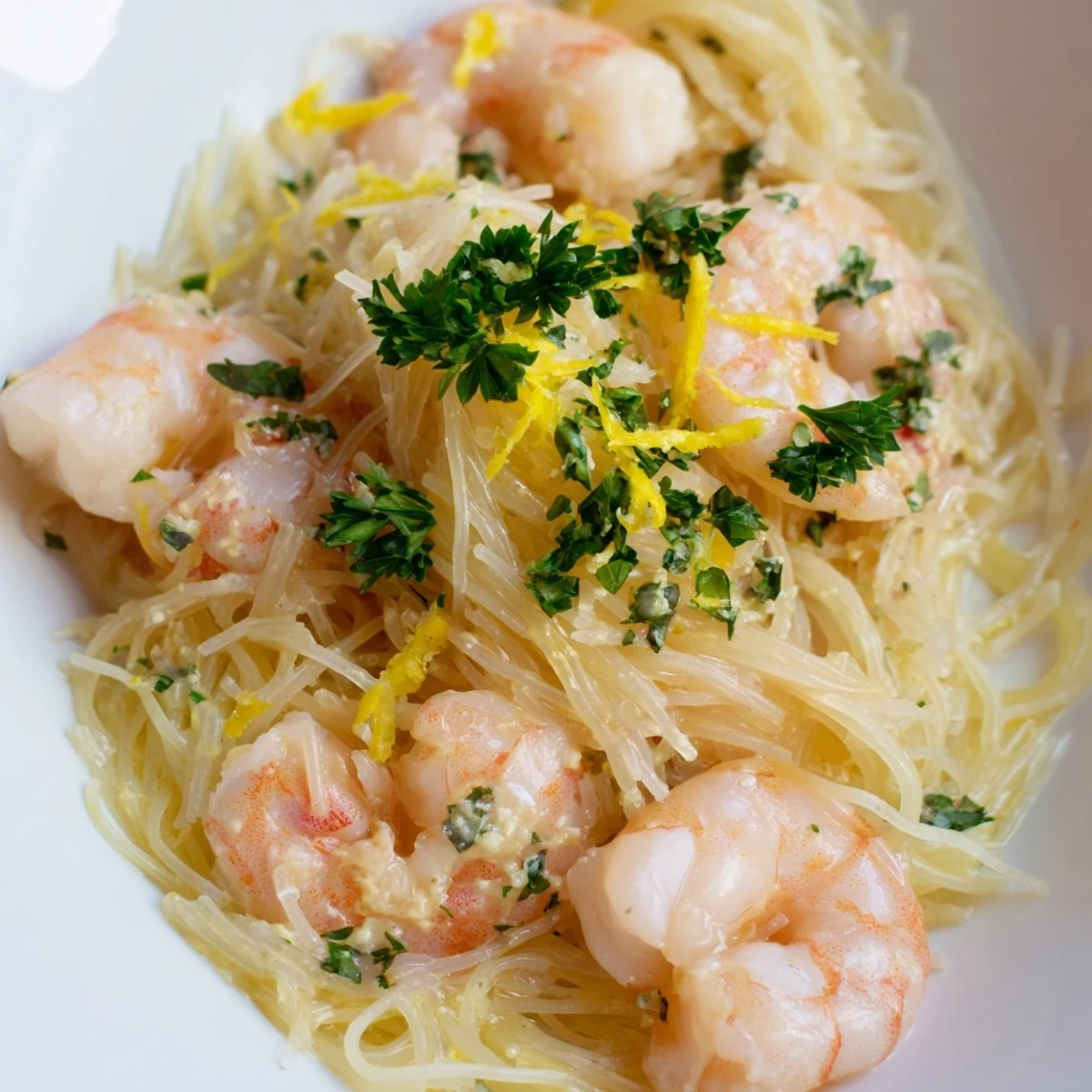 A steaming plate of Lemon Butter Shrimp Pasta Lite featuring tender shrimp coated in a bright, buttery lemon sauce and delicate pasta strands.