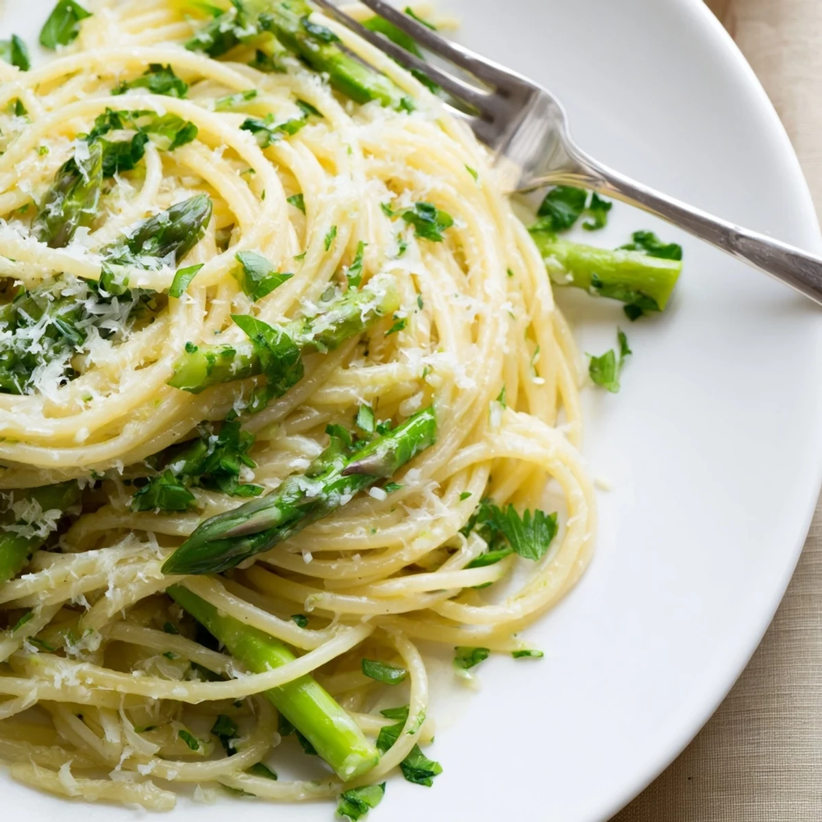 A close-up of Roasted Garlic & Asparagus Pasta with golden roasted garlic cloves and bright green asparagus spears tangled in olive oil-coated spaghetti.
