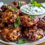 Hearty cauliflower bhajis with vibrant spices are served hot alongside a creamy, tangy yogurt dip.