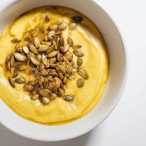 A steaming bowl of creamy roasted pumpkin soup, perfect for a cozy fall evening.