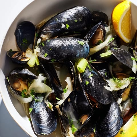 Beautiful photo of Belgian Moules Marinière: plump, briny mussels swimming in savory white wine broth.