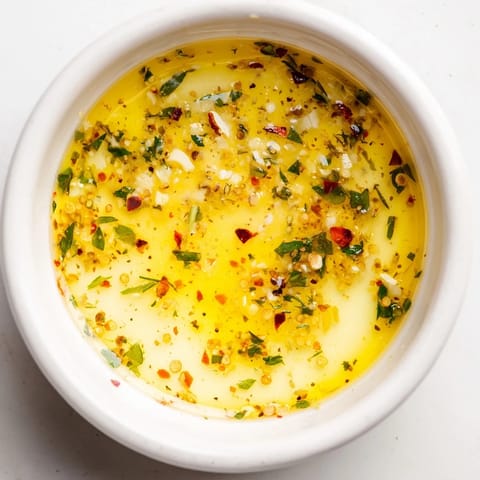 A close-up of a small bowl of Cowboy Butter Sauce, garnished with fresh parsley and chives, ready for dipping.  