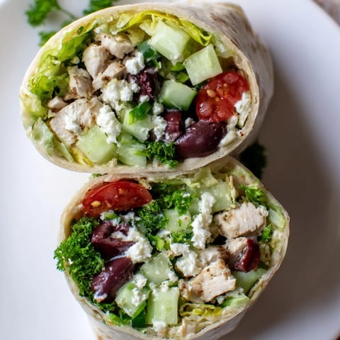Bright Mediterranean flavors shine in this Greek Lemon Chicken Salad Wrap, filled with crisp veggies and tangy feta, served on a rustic wooden board. 