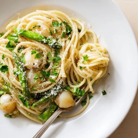 Plated Roasted Garlic & Asparagus Pasta garnished with fresh parsley, lemon zest, and shaved Parmesan, steam rising from the tender spring vegetables.