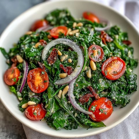 Zesty dandelion greens tossed in lemon vinaigrette, topped with Parmesan, cherry tomatoes, and pine nuts for a vibrant vegetarian salad.