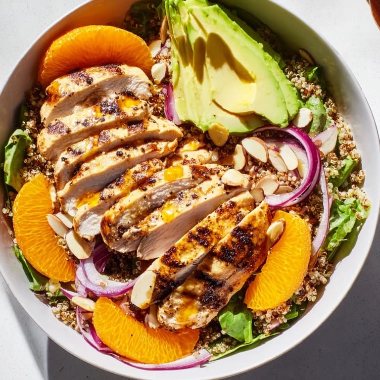 A fork lifts bright citrus vinaigrette over a hearty Citrus Herb Chicken Salad Bowl with sliced chicken.