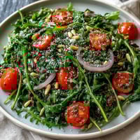 Bright dandelion greens salad with lemon vinaigrette and Parmesan shavings, cherry tomatoes, and toasted pine nuts for a fresh, zesty bite.